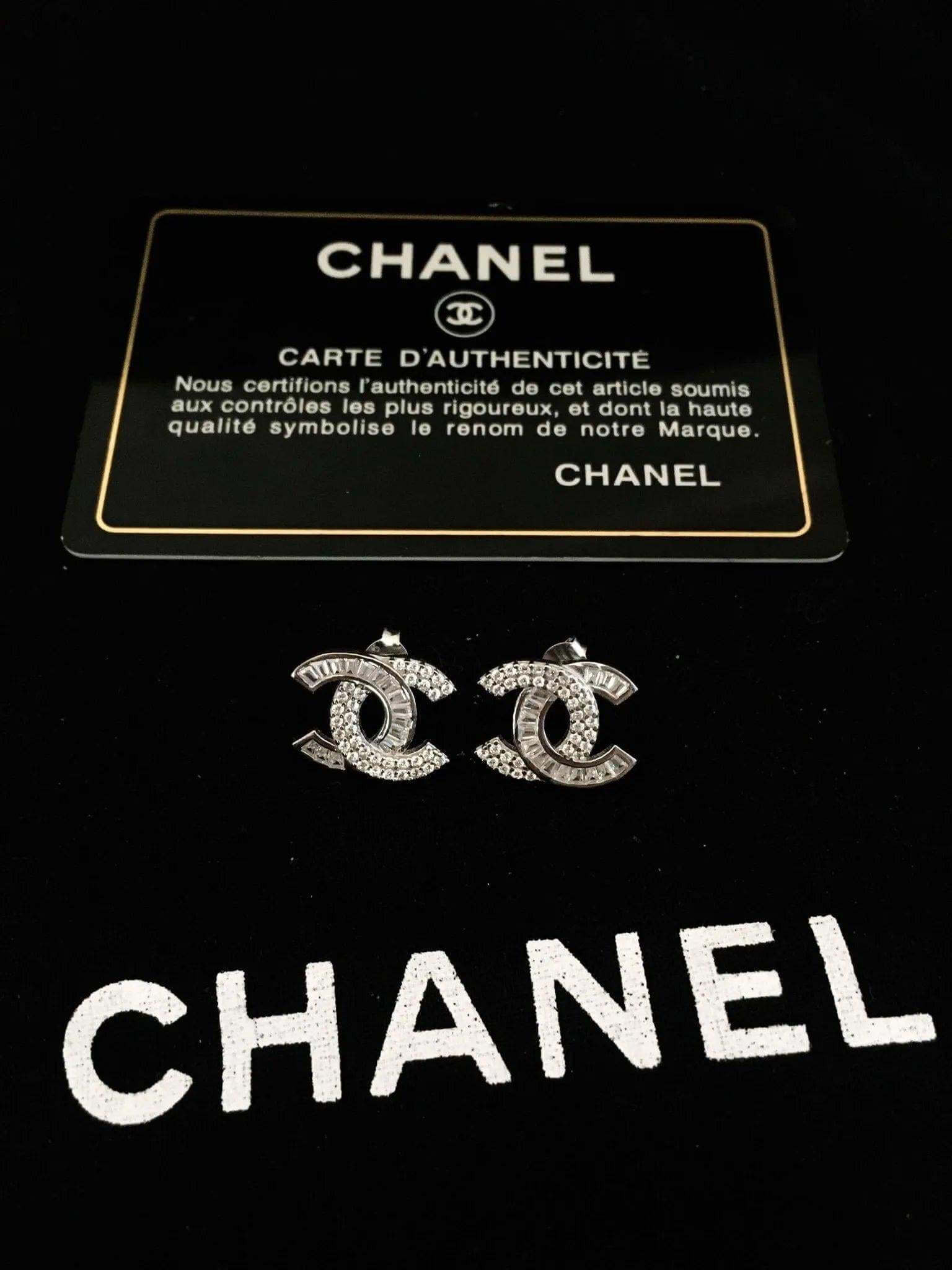 Authentic Chanel stud earrings in 925 sterling silver with white zircon baguette stones and Chanel authenticity card on black background