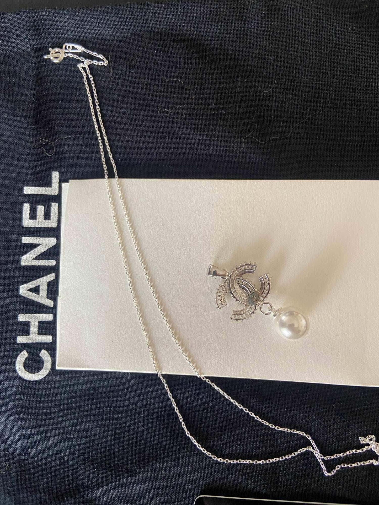 Authentic Chanel Jewelry 925 sterling silver necklace with pearl and baguette stones on black and white Chanel packaging