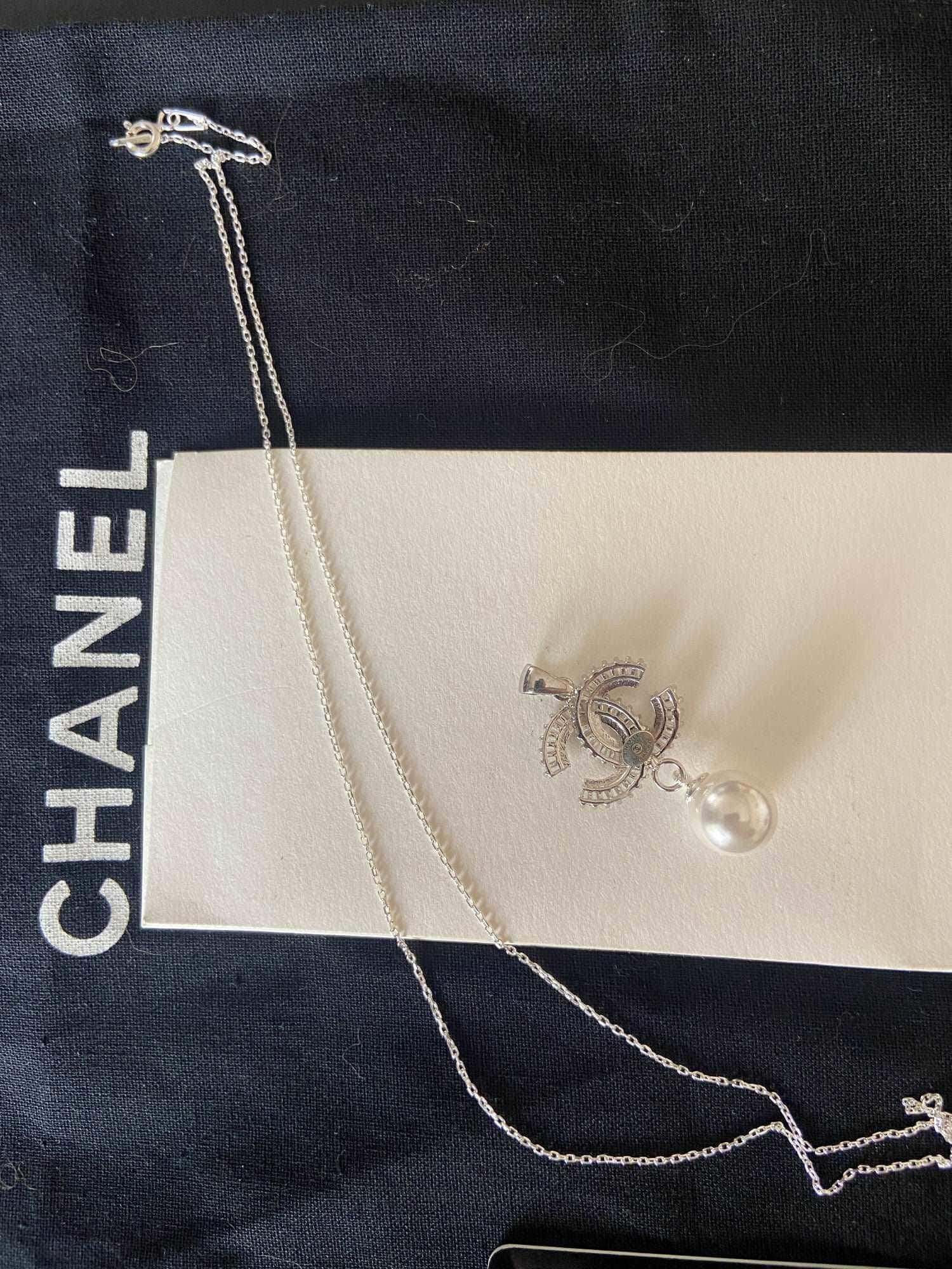 Authentic Chanel Jewelry 925 sterling silver necklace with pearl and baguette stones on black and white Chanel packaging