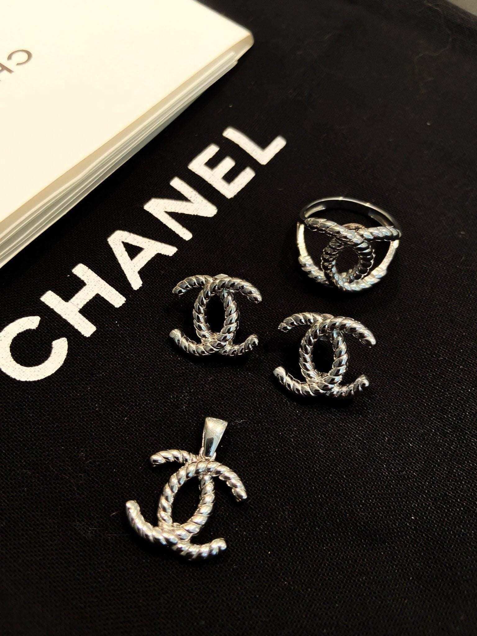 Vintage Chanel Set 925 sterling silver earrings ring and pendant on black background with Chanel logo text