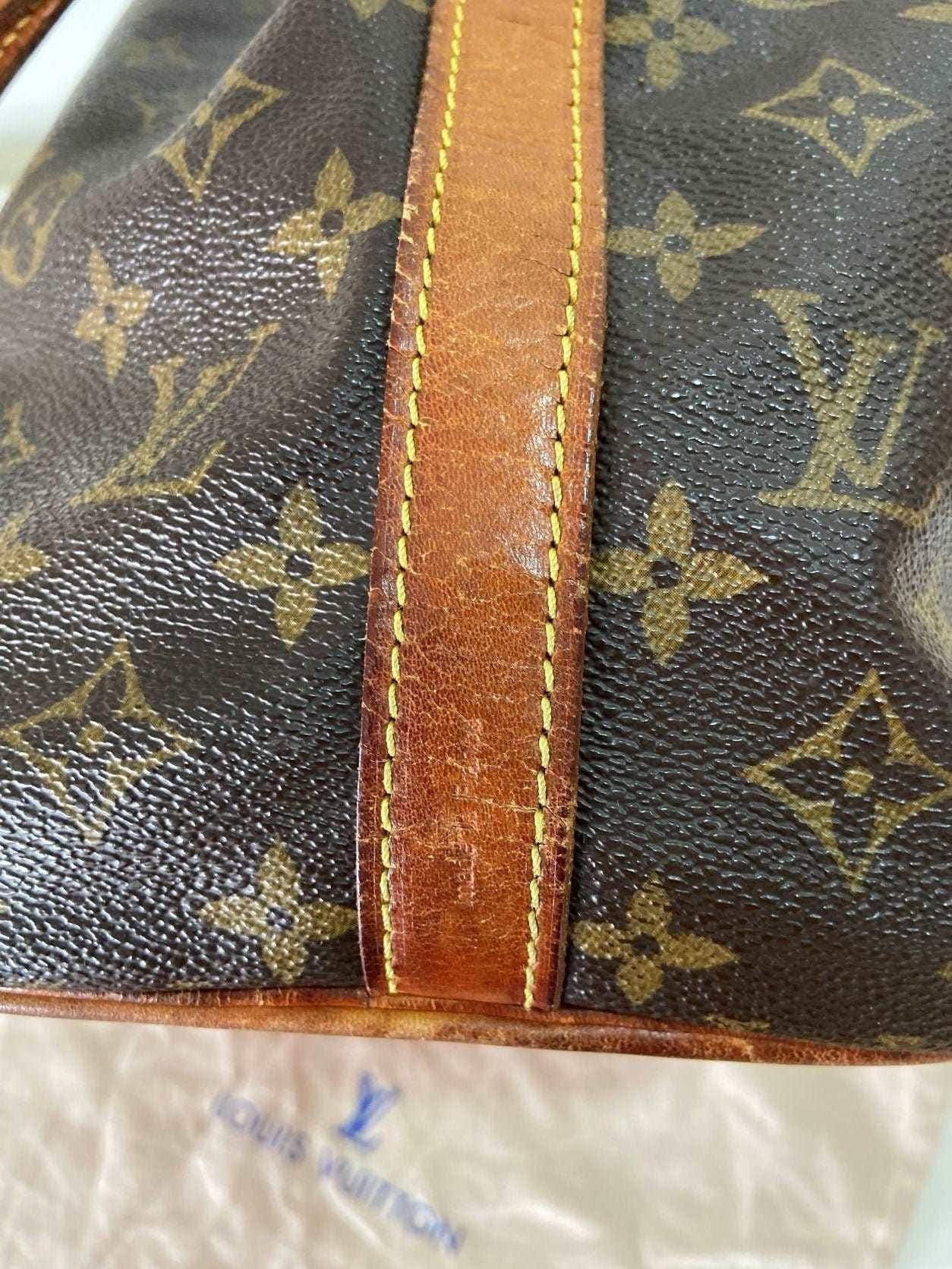 Close-up of authentic Louis Vuitton Noe bag monogram canvas and worn leather strap detail