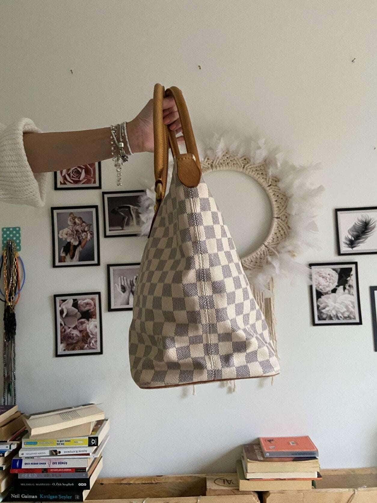 Louis Vuitton Damier Azur Saleya MM tote bag with leather handles held indoors with wall art background
