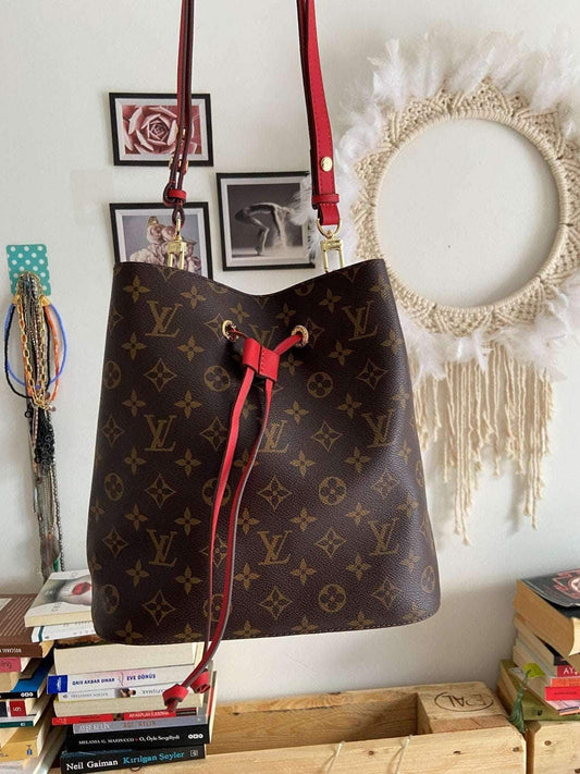 Louis Vuitton NÉONOÉ handbag in monogram canvas with red leather trim and adjustable strap hanging indoors