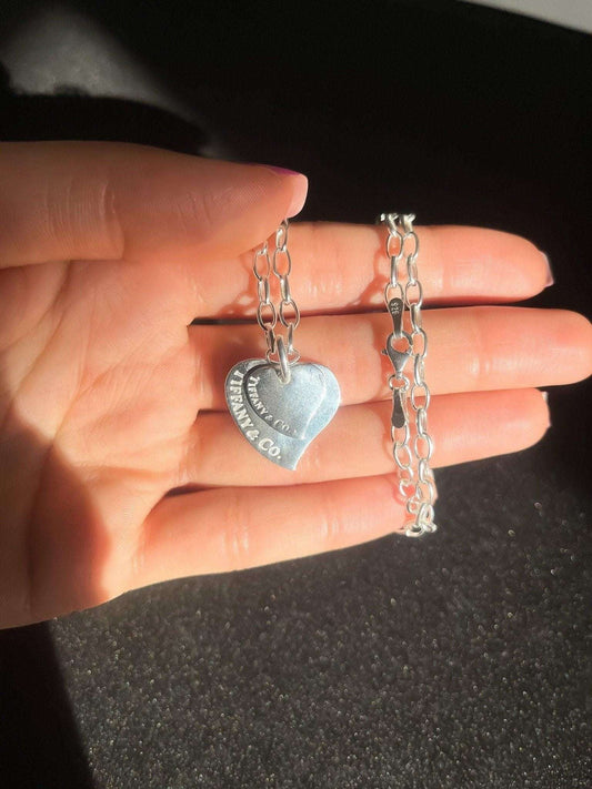 Tiffany&Co. 925 sterling silver heart necklace held in hand with chain links visible