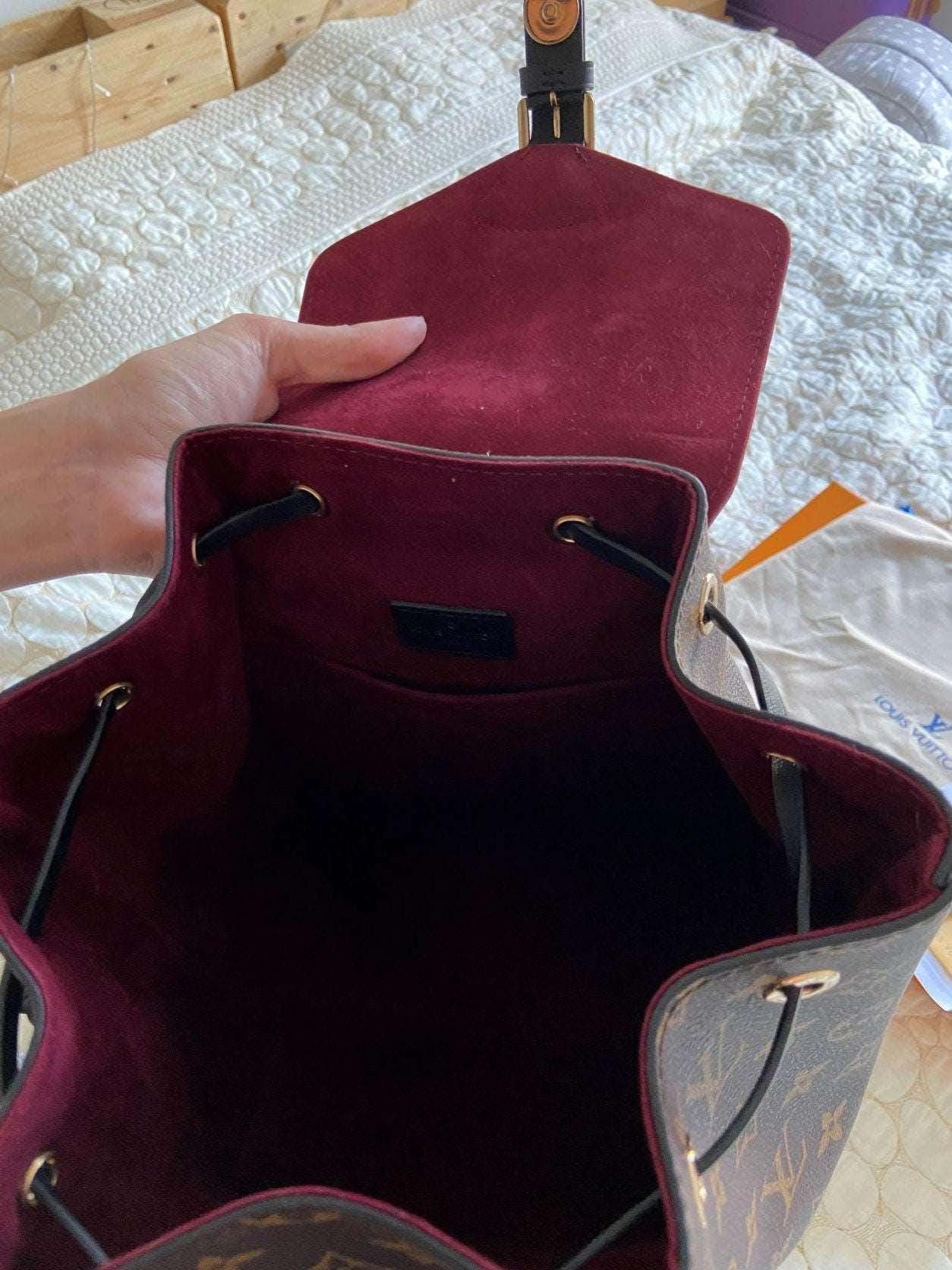 Open Louis Vuitton Monogram MONTSOURIS Backpack showing spacious burgundy interior lining